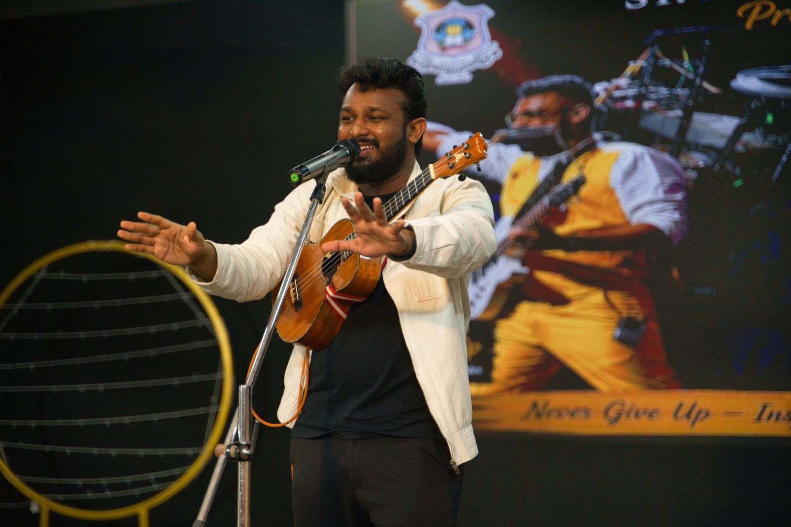 Gladson Peter singing with ukulele, arms open to the audience